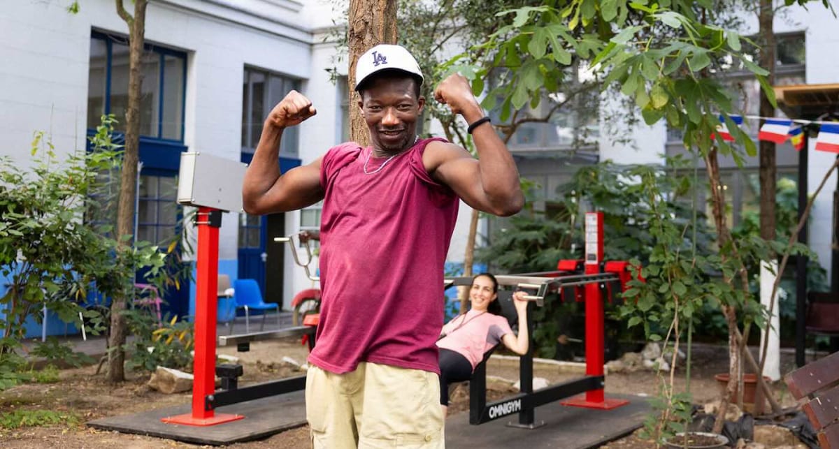 Person exercising on outdoor gym equipment installed at homeless shelter courtyard in Paris