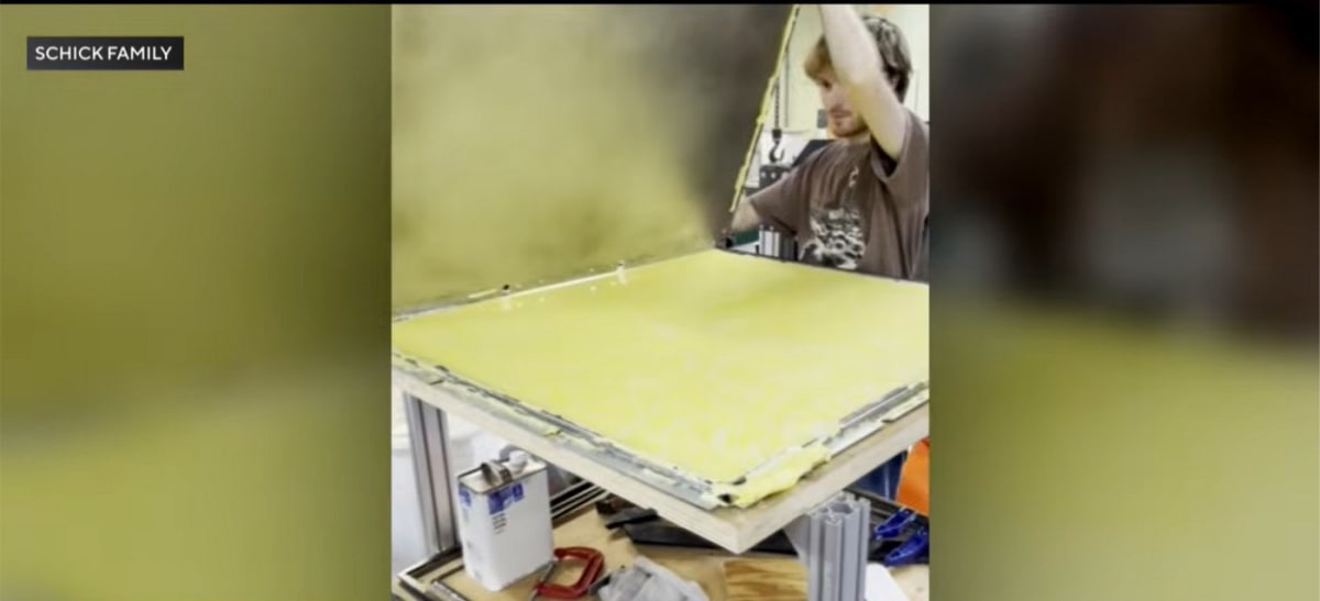 Young Nick Schick removes a large molded plastic sheet from manufacturing equipment at Peninsula Precious Plastics workshop