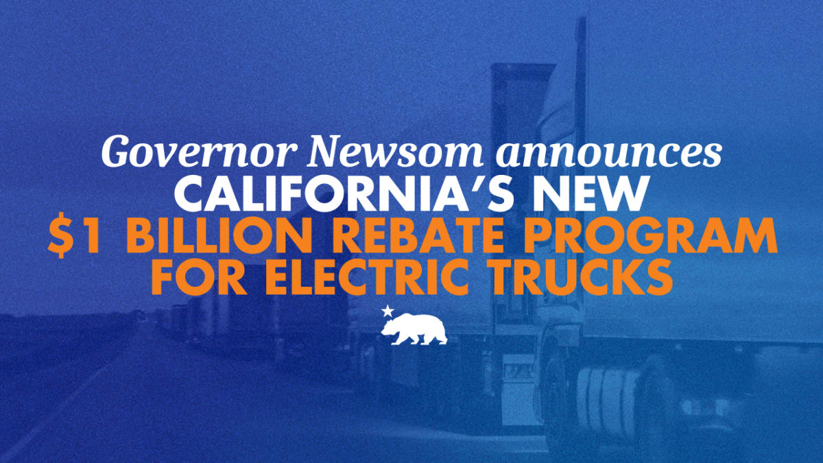 Electric semi-truck charging at commercial station with California freight corridor in background