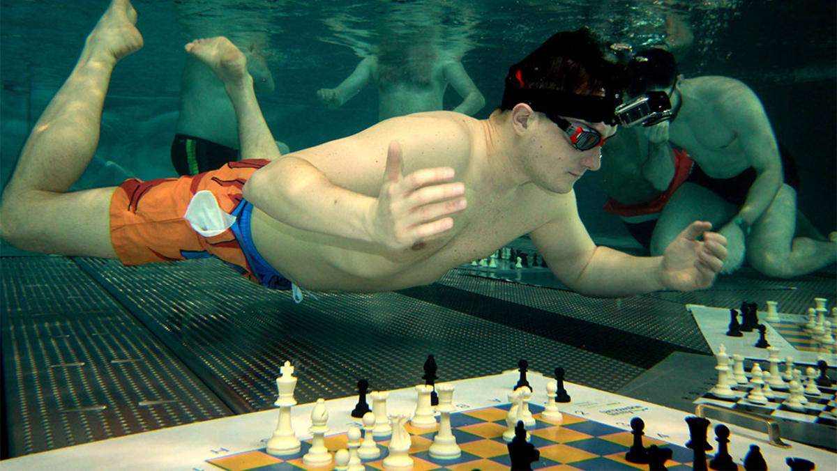 Polish chess player Michał Mazurkiewicz competing underwater with chess board at pool bottom