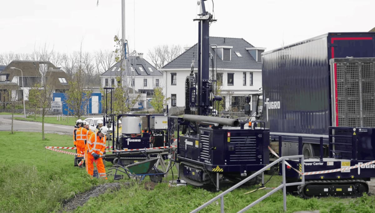 Construction survey equipment at pipeline route site in Dutch industrial area along waterway