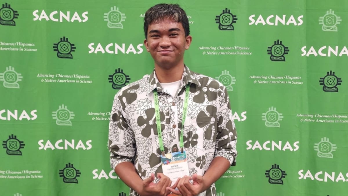 Masen Lapinad-Sorgent holding research awards at SACNAS Conference in traditional Hawaiian attire