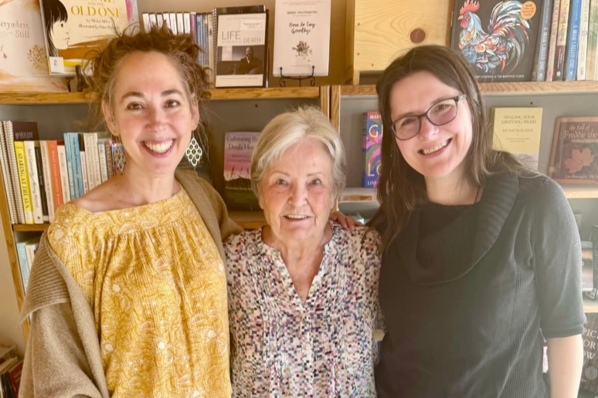 ** Three women standing together in hospice office, including long-time volunteer and staff members