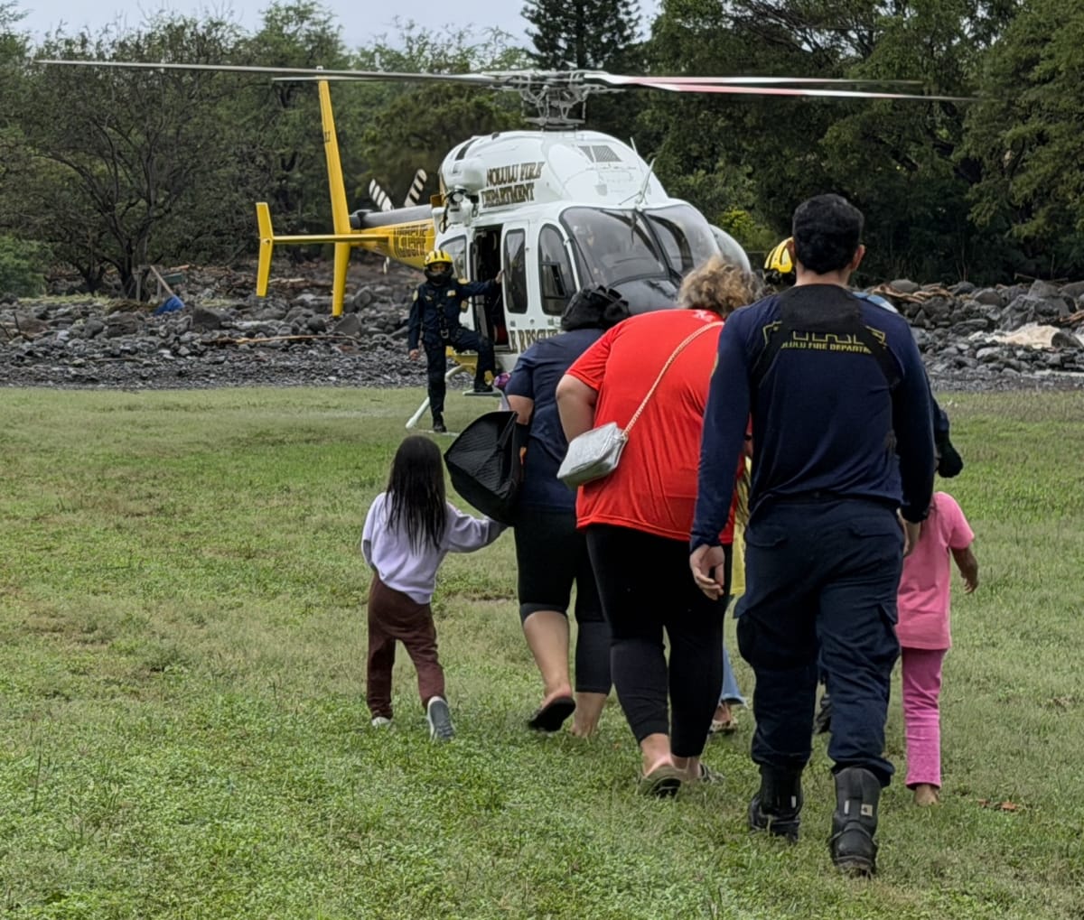 Honolulu firefighters in safety gear conducting rescue operations during severe island storm conditions