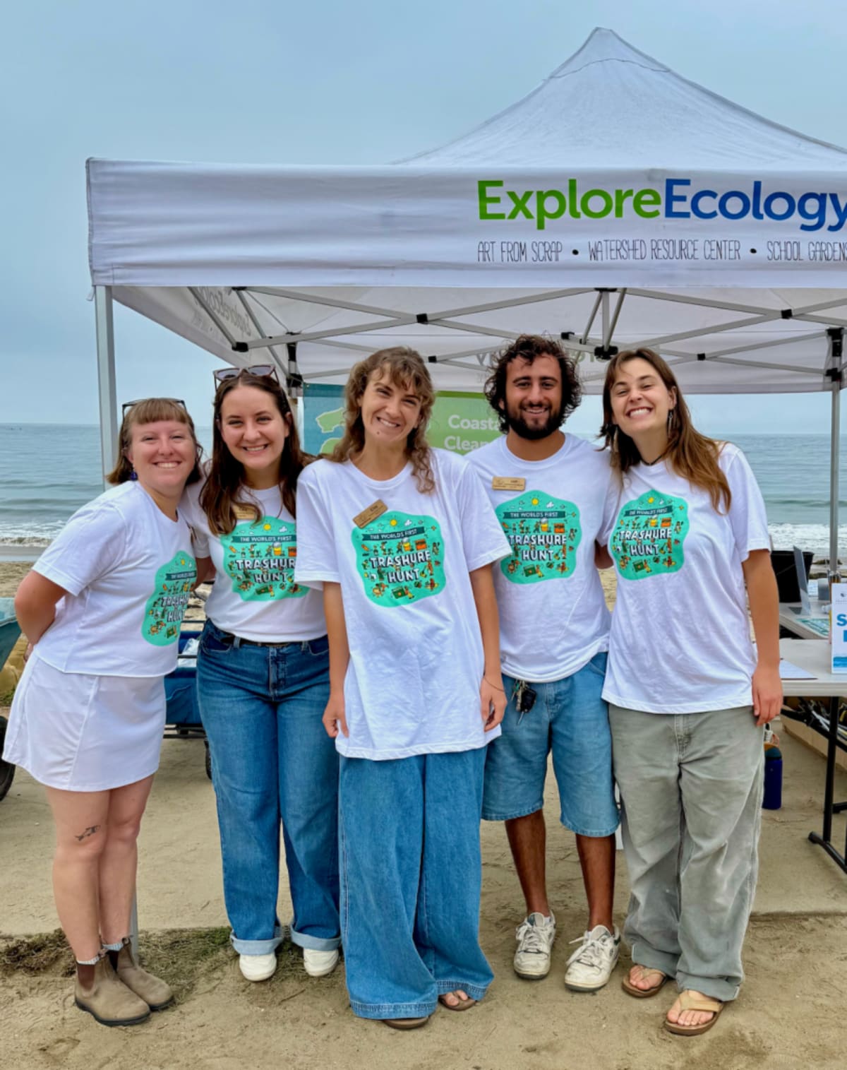 Volunteers in gloves collecting plastic waste and litter along sunny California coastline