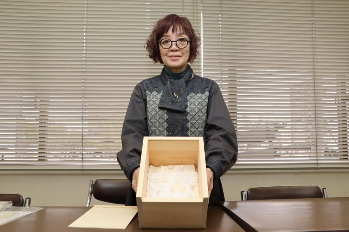 Compassionate Japanese nurse Masako Sugami holding small dignified baby coffin with bedding