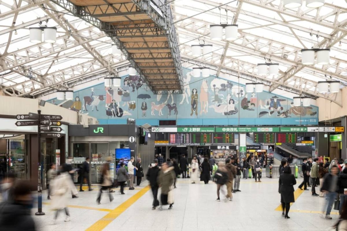 Large pentagonal mural titled Freedom hangs above crowded Ueno Station gate in Tokyo Japan