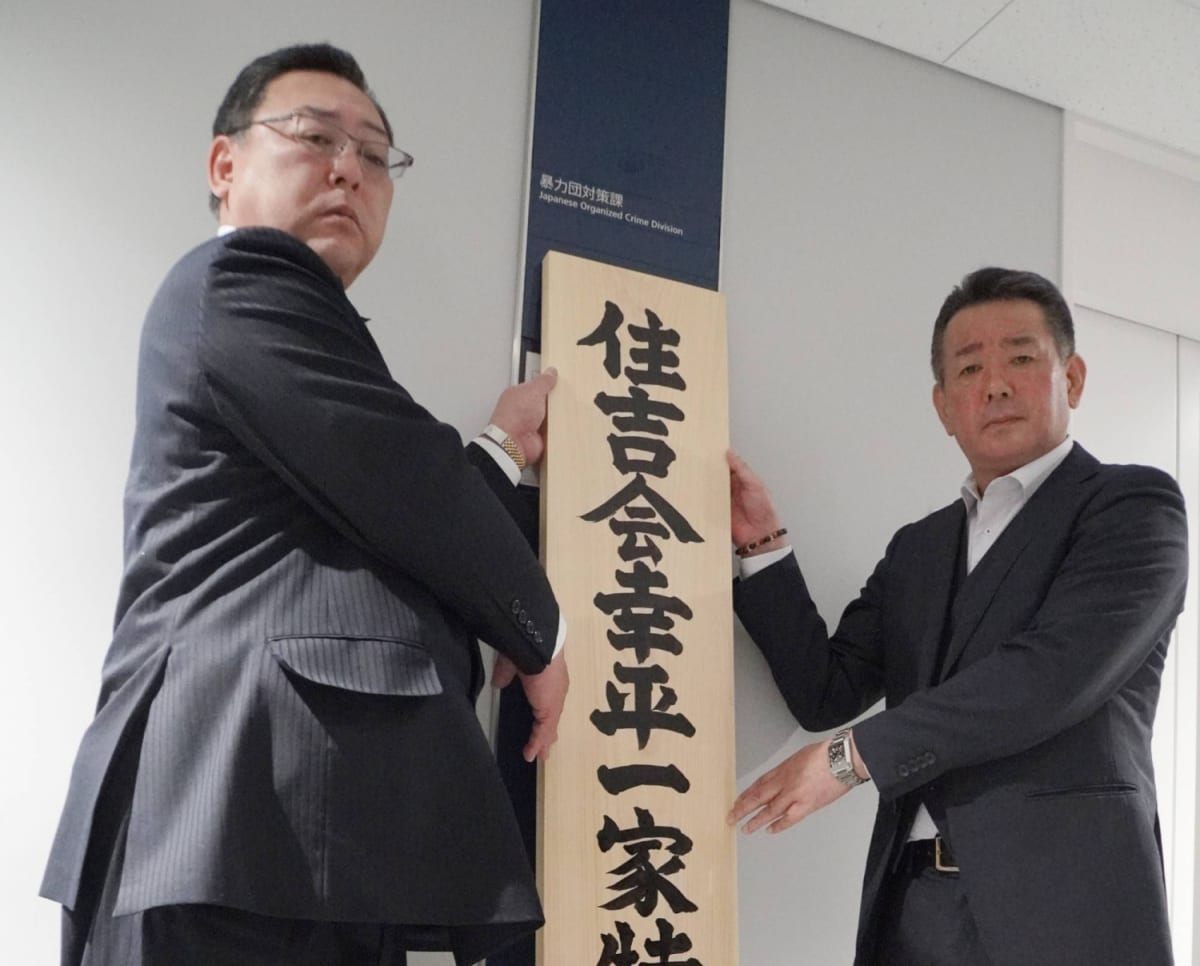 Japanese police station exterior with officers on patrol representing organized crime reduction efforts