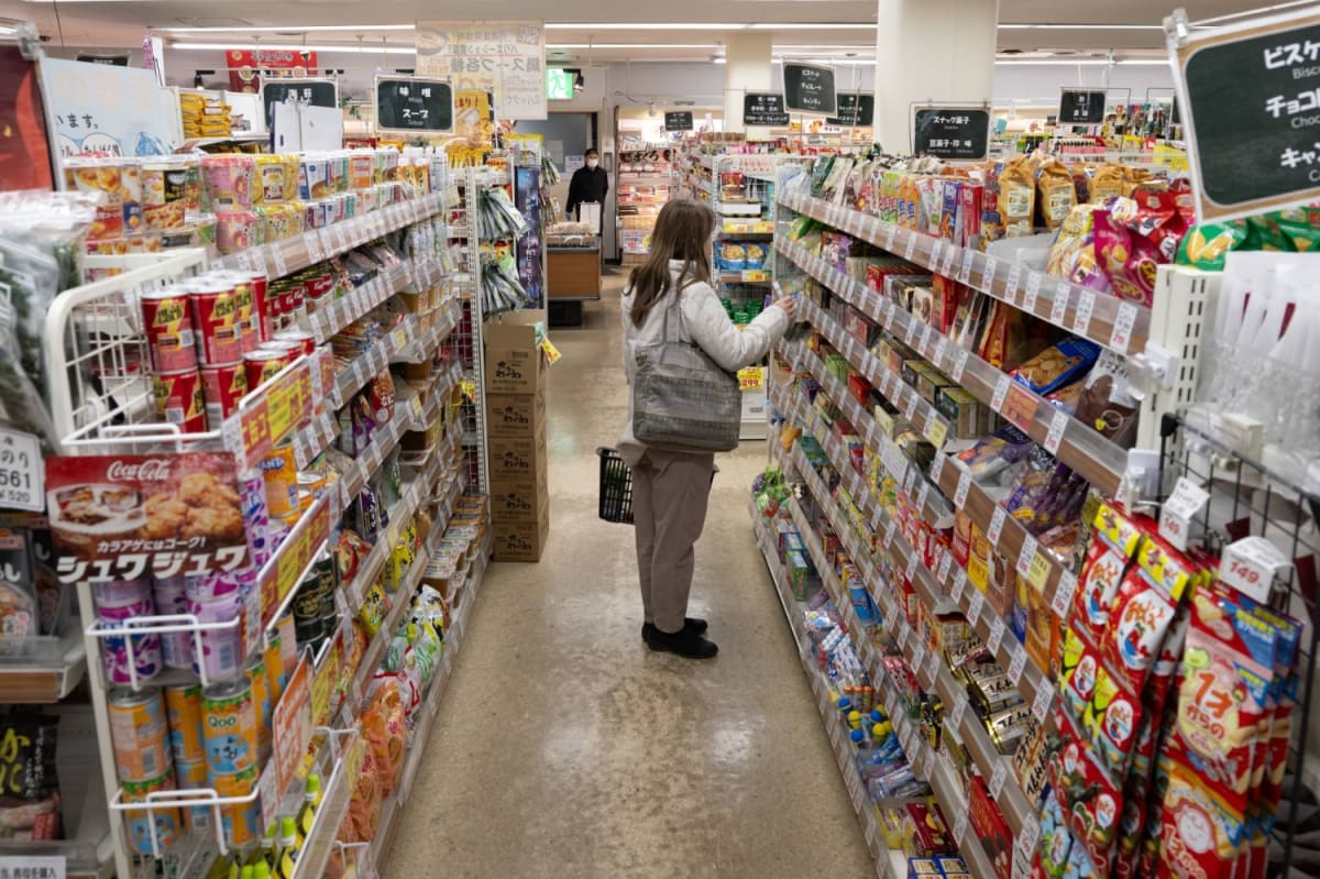 Smartphone scanning QR code on food package in Japanese grocery store aisle