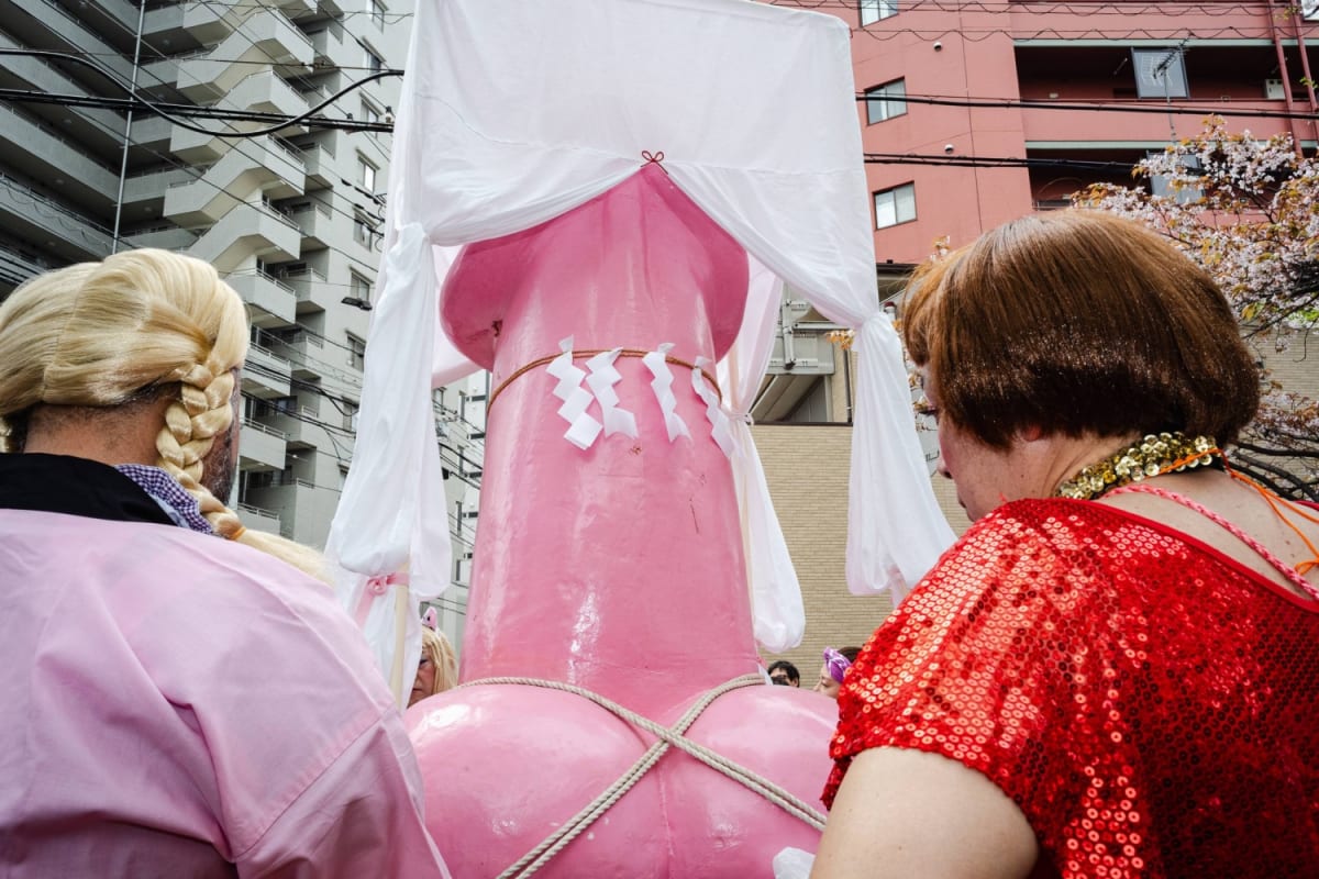 Pink portable shrine called Elizabeth carried through crowded streets at Kanamara Festival in Kawasaki, Japan