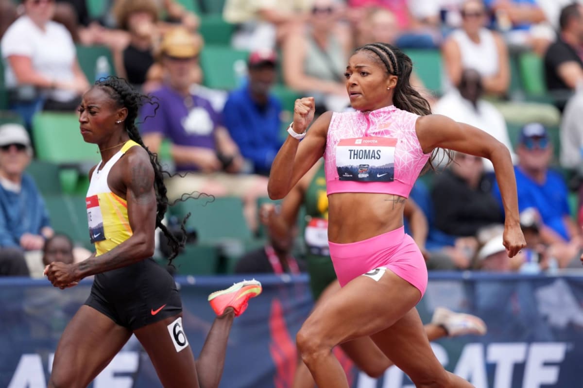 Female track athletes competing on outdoor stadium track during international athletics competition