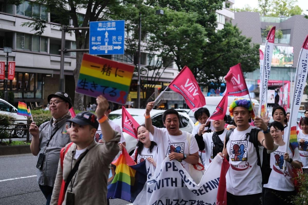 Thousands of people march through Tokyo streets waving colorful rainbow Pride flags in the rain