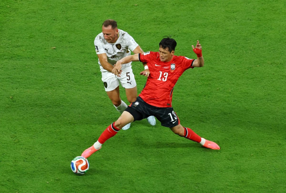 South Korean soccer players celebrating goal while Mexican fans cheer in packed stadium