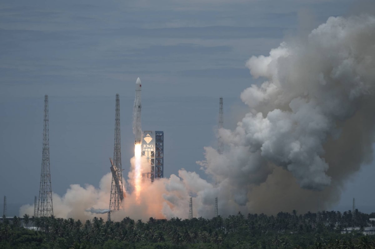 Rocket booster descending vertically toward net recovery system on ocean platform