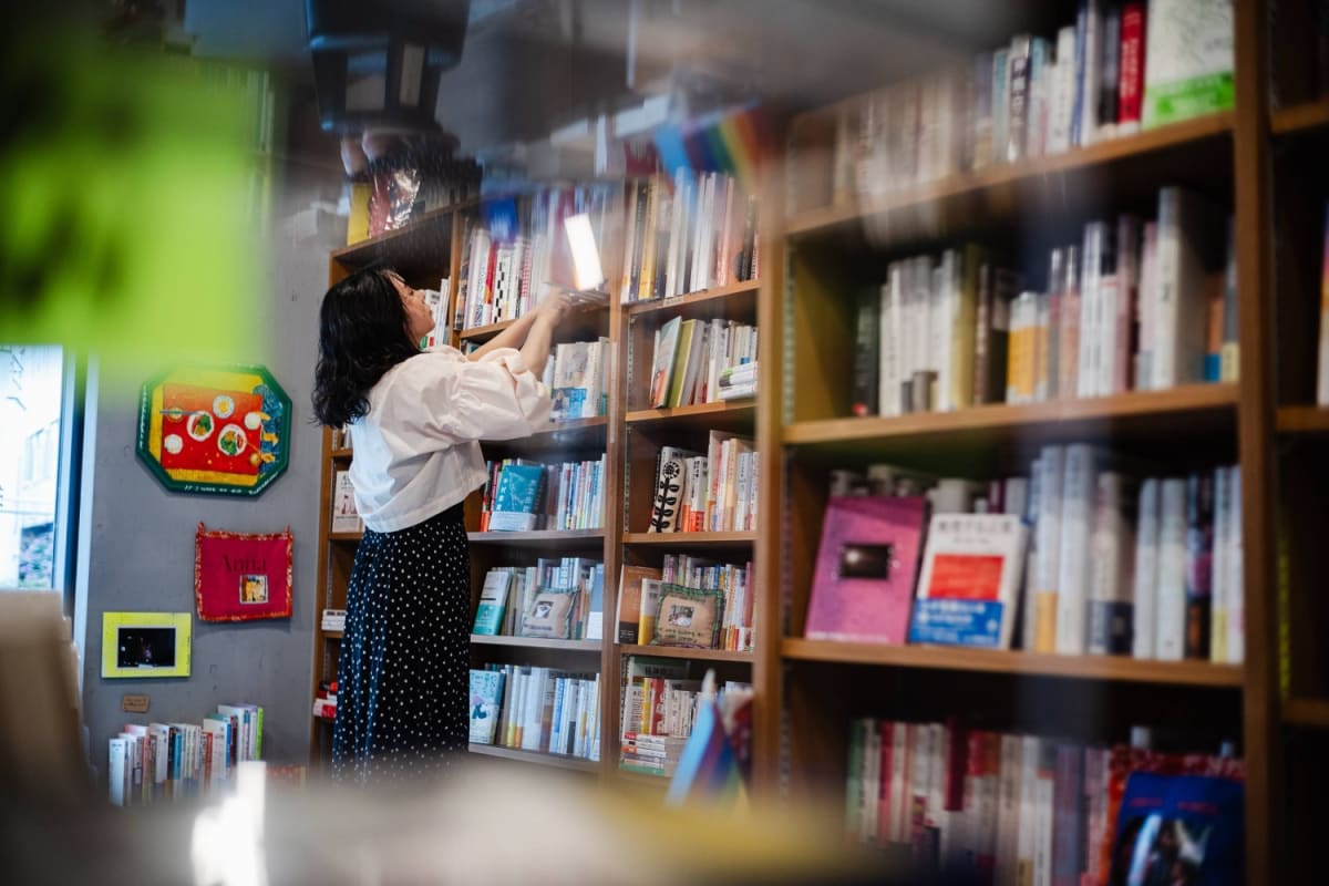 Cozy Tokyo bookstore with shelves filled with diverse feminist books and reading space