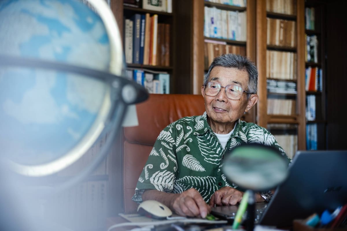 Elderly Japanese scientist Katsutada Kaminuma examining a detailed map of Antarctica at his home