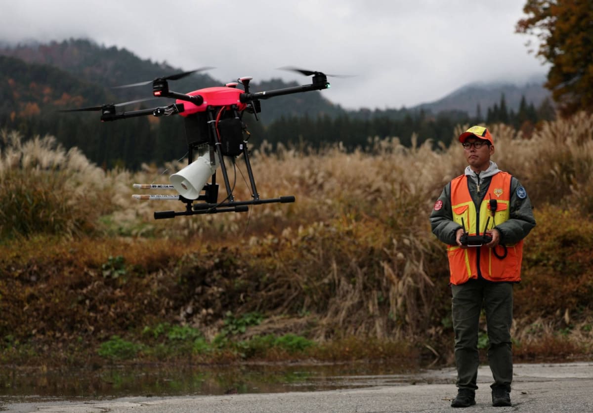 Drone flying over forested mountain area near Japanese residential neighborhood monitoring for bear activity