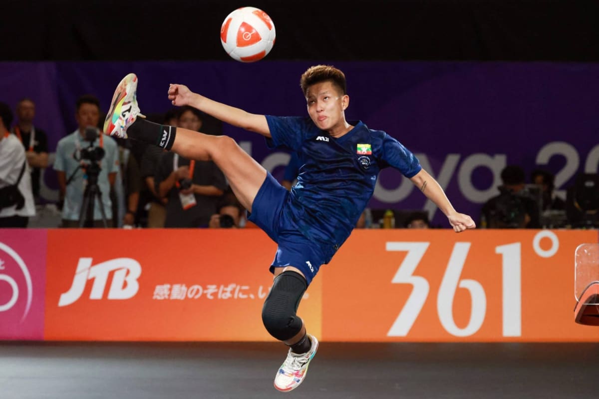 Female athlete kicking soccer ball over curved teqball table during Asian Games competition