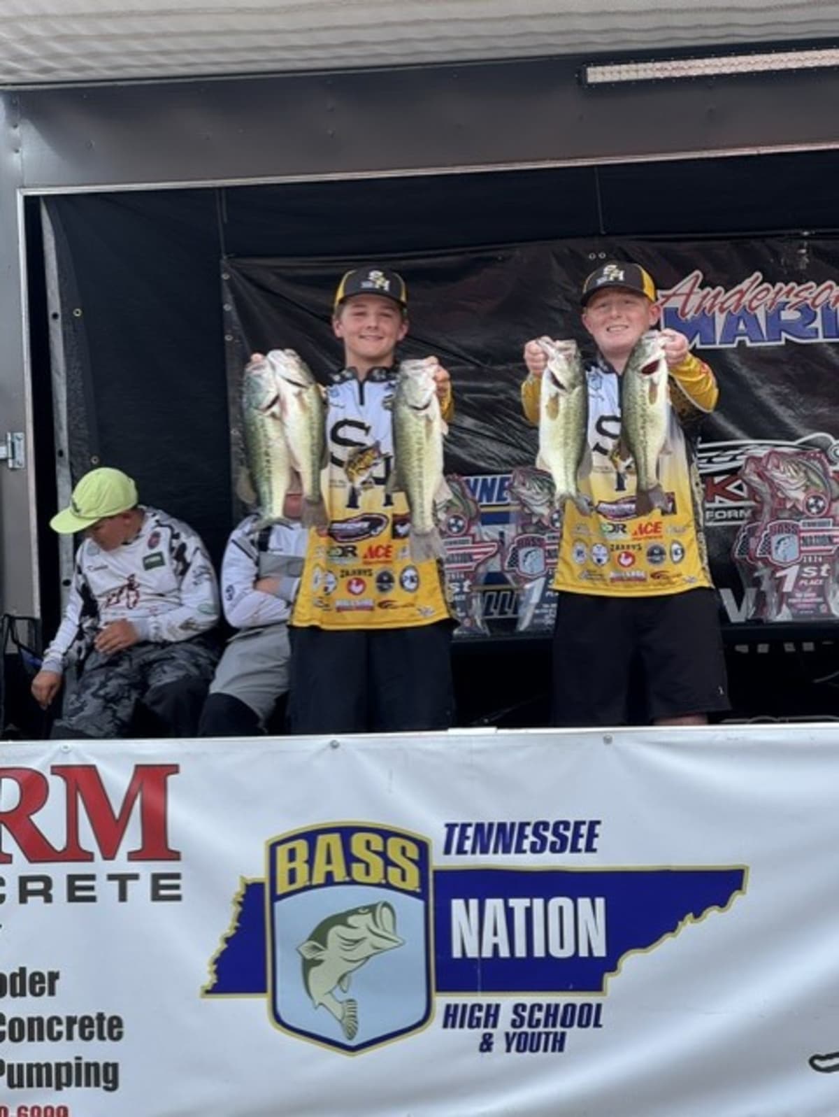Two teenage anglers holding bass fish and trophy after winning Tennessee state championship