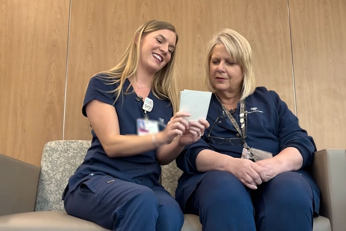** Smiling nurse in scrubs standing in hospital neonatal intensive care unit with incubators