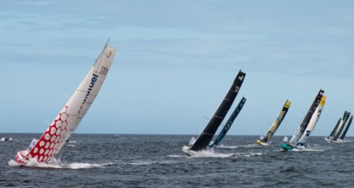 ** Multiple Class 40 sailing boats with white sails racing across blue ocean waters