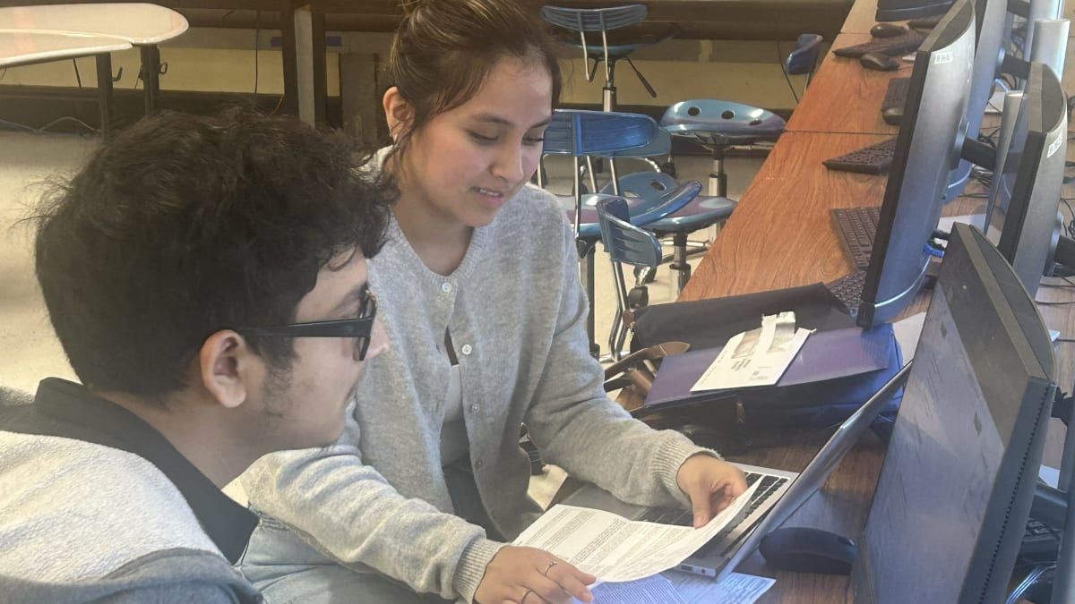 High school students helping community members complete tax forms in bright classroom setting