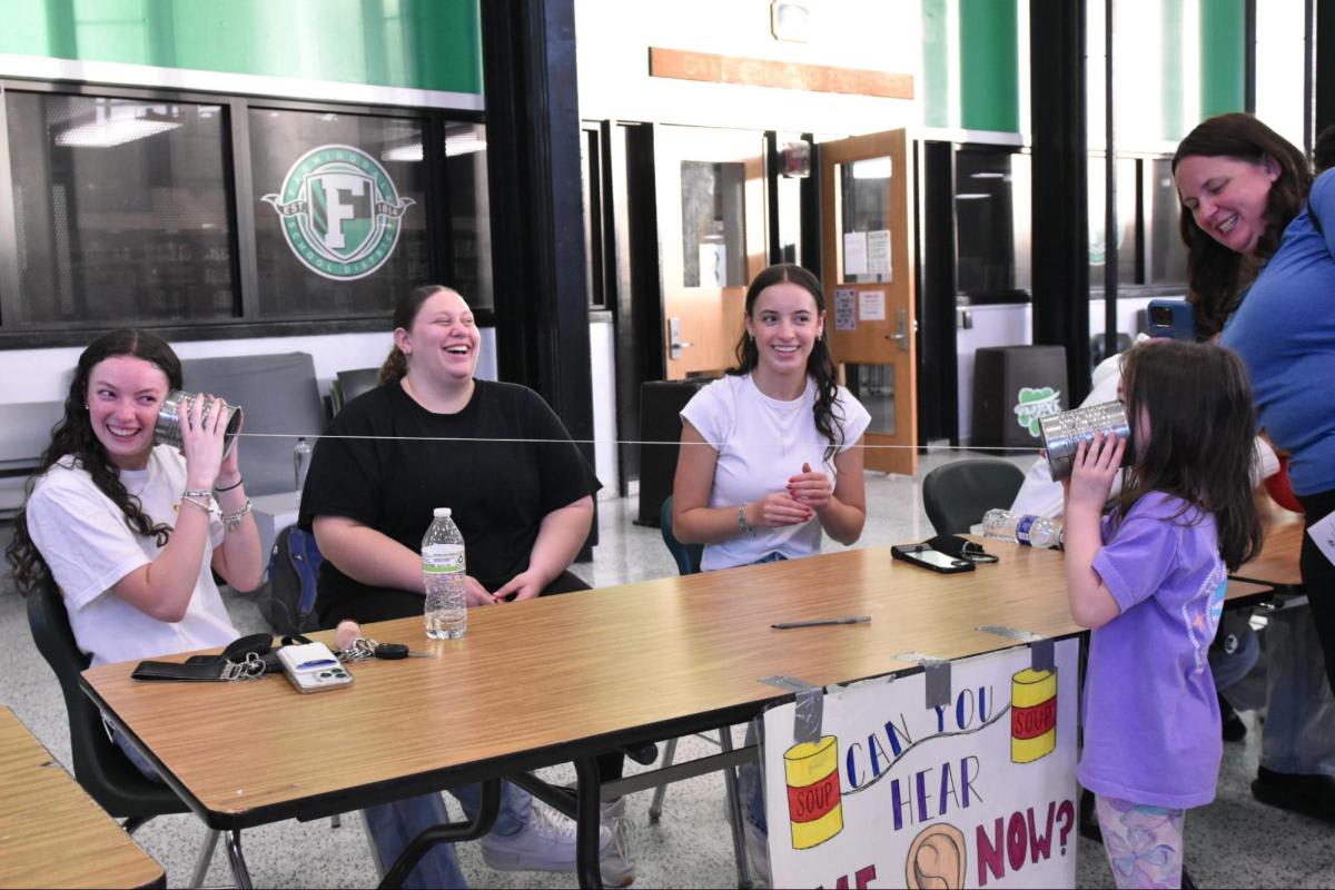 Elementary students experiment with sound wave conduction using connected tin cans at STEAM Night