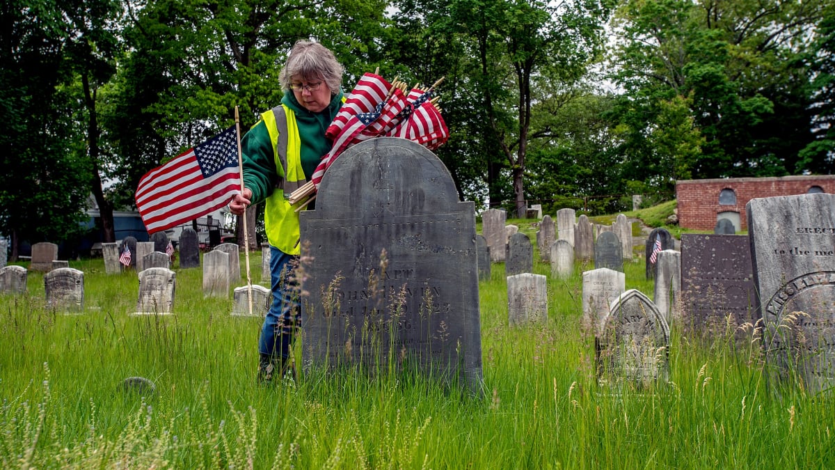 American flags placed in rows at veterans' graves in historic Framingham cemetery