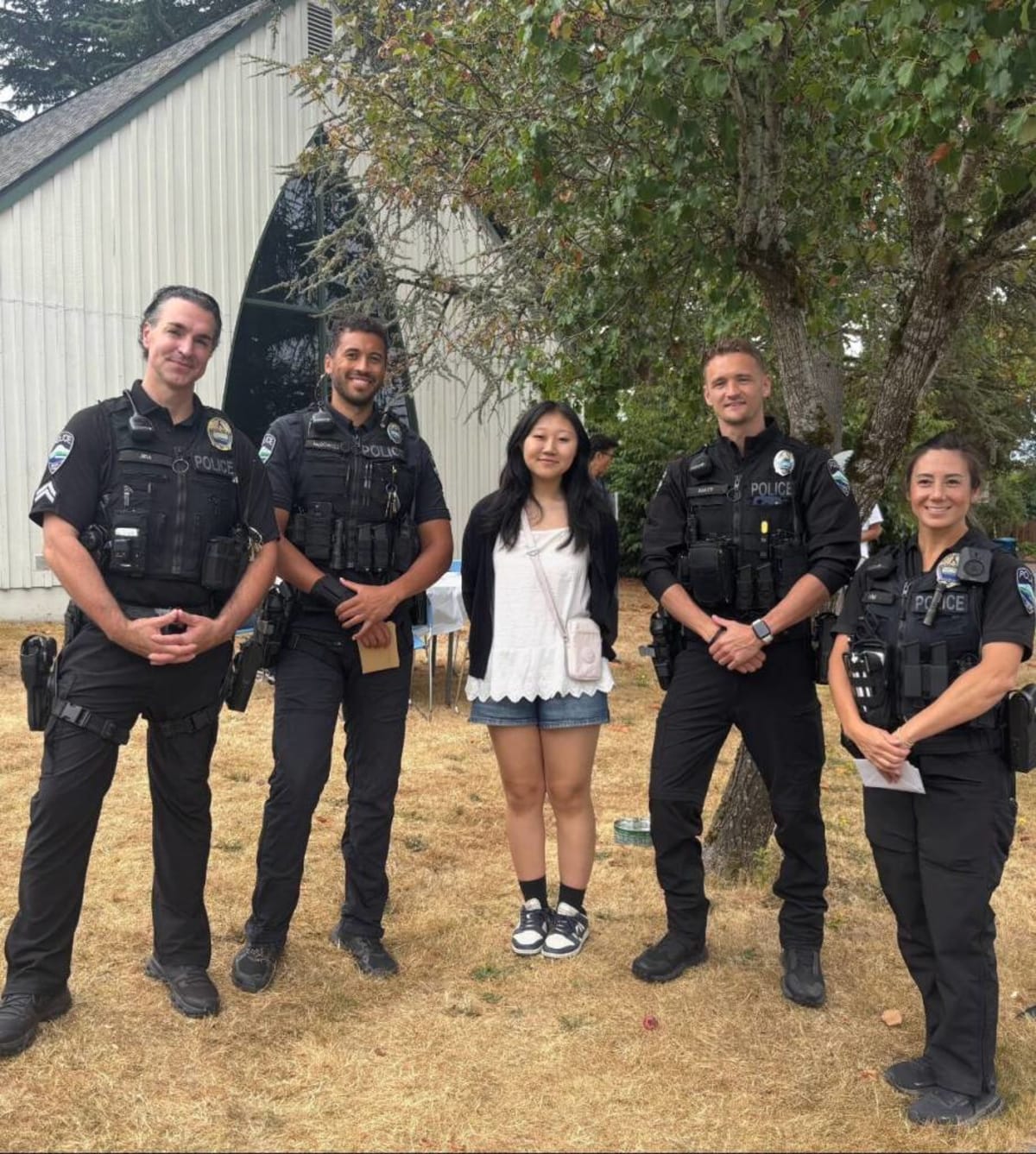 High school student Gloria Go standing with four Mercer Island police officers at outdoor ice cream fundraiser event