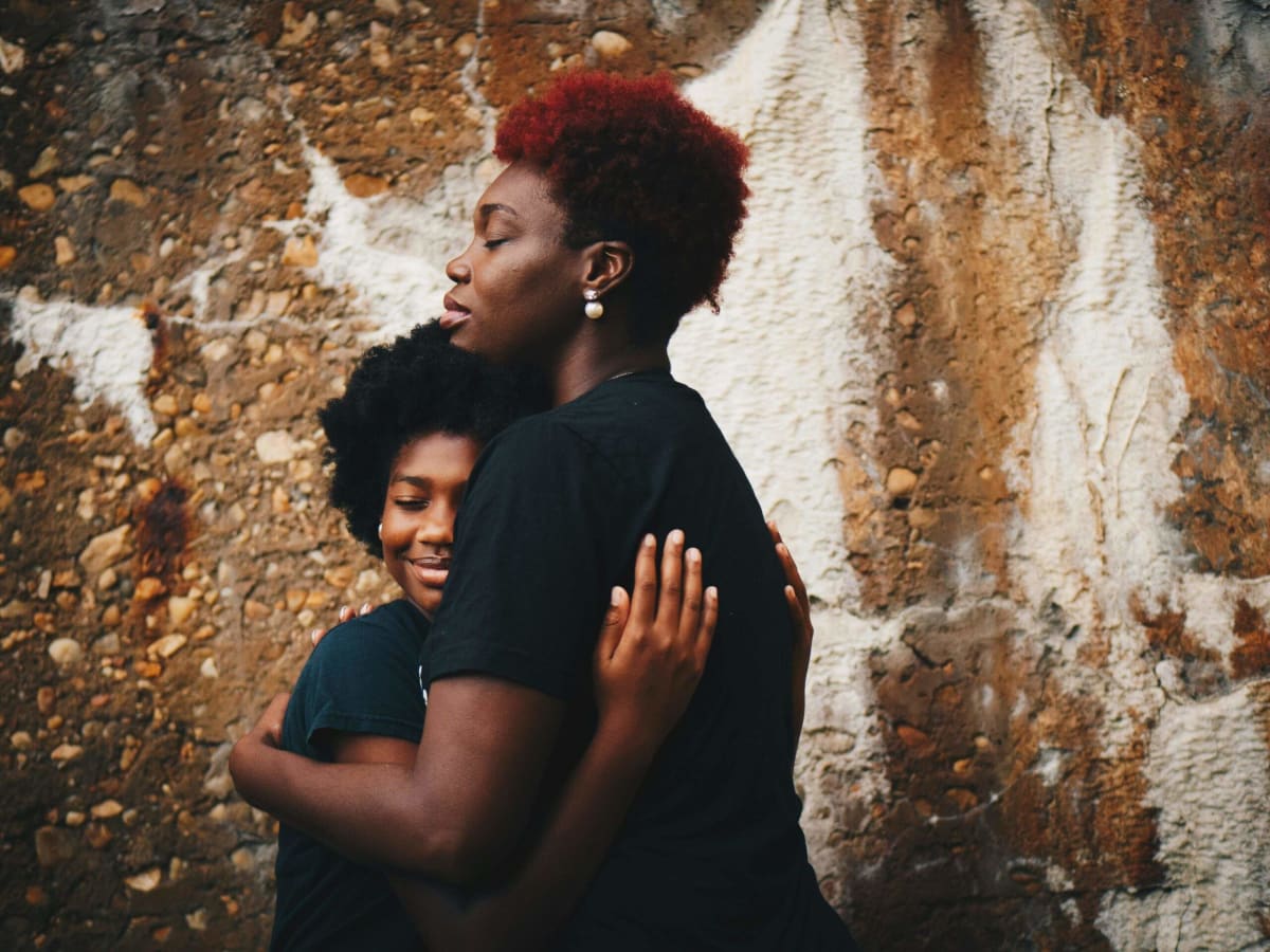 ** Young girl sitting thoughtfully with parent, learning to process emotions about shelter dogs