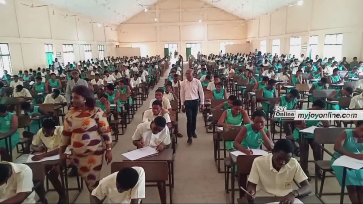 Ghanaian students sitting at desks taking written examinations in a classroom