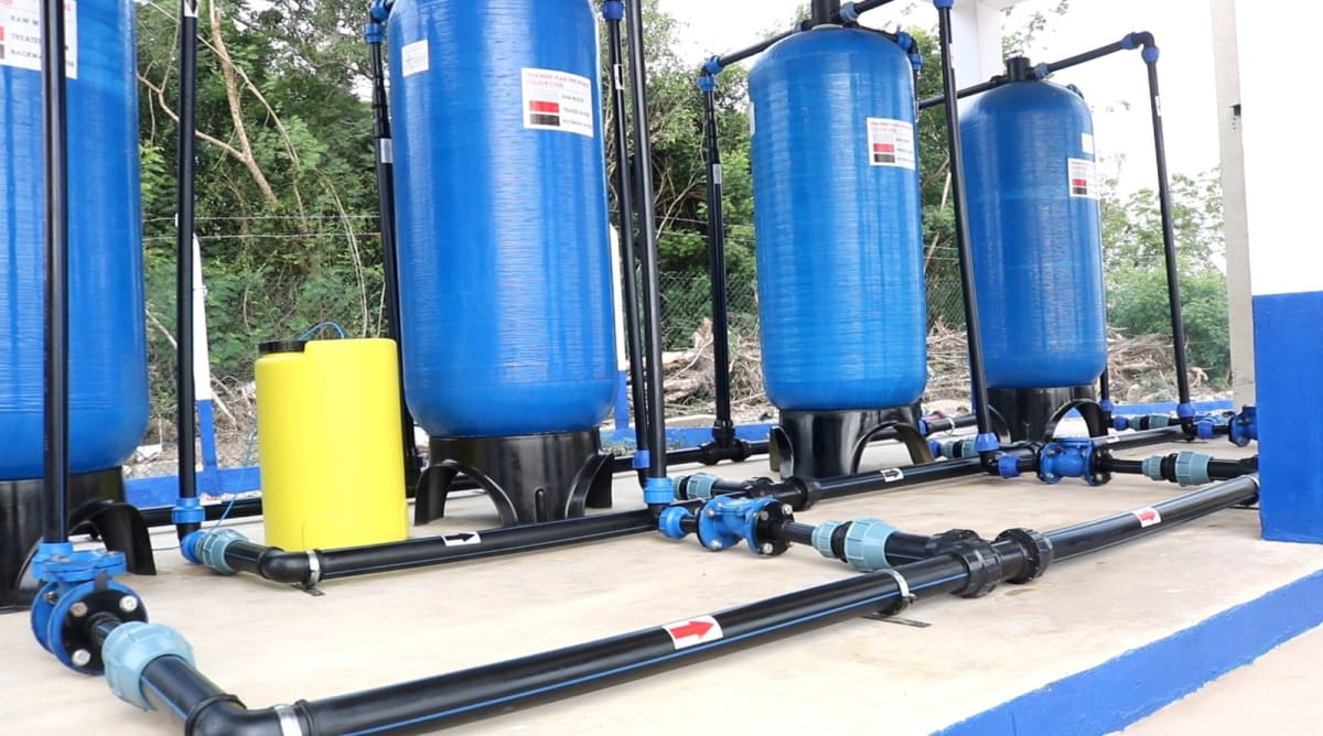 Modern water standpipe in Ghanaian coastal community with residents gathering around celebrating new water access