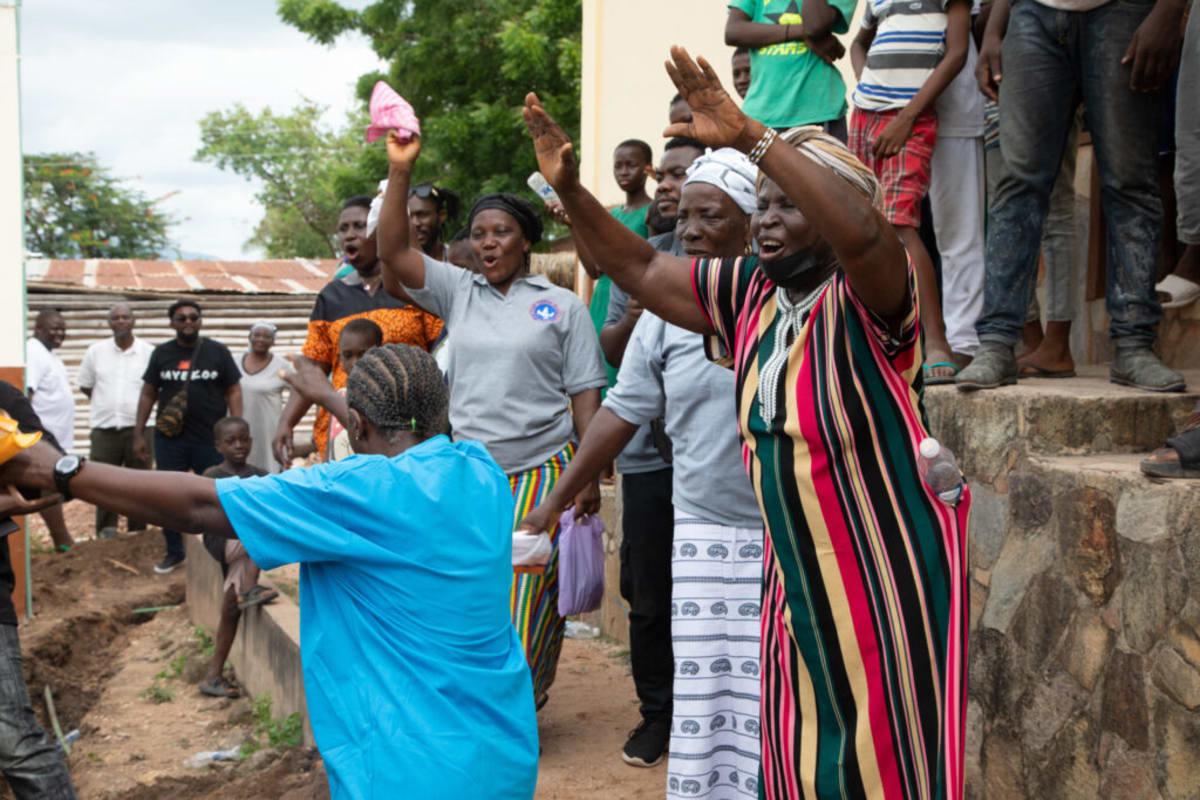 Ghanaian primary school students gathering around newly installed water borehole facility in rural community
