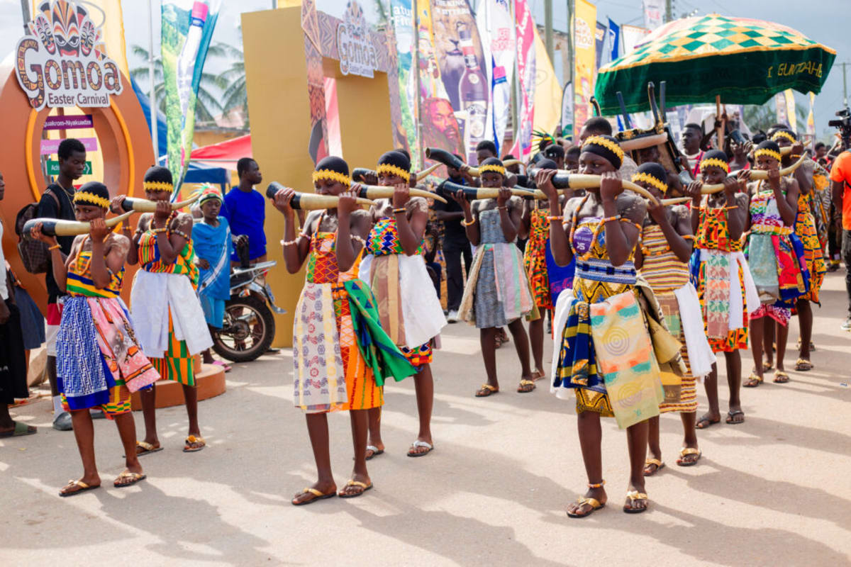 Festival-goers in vibrant traditional Ghanaian attire celebrating at Gomoa Easter Carnival with dancing and music