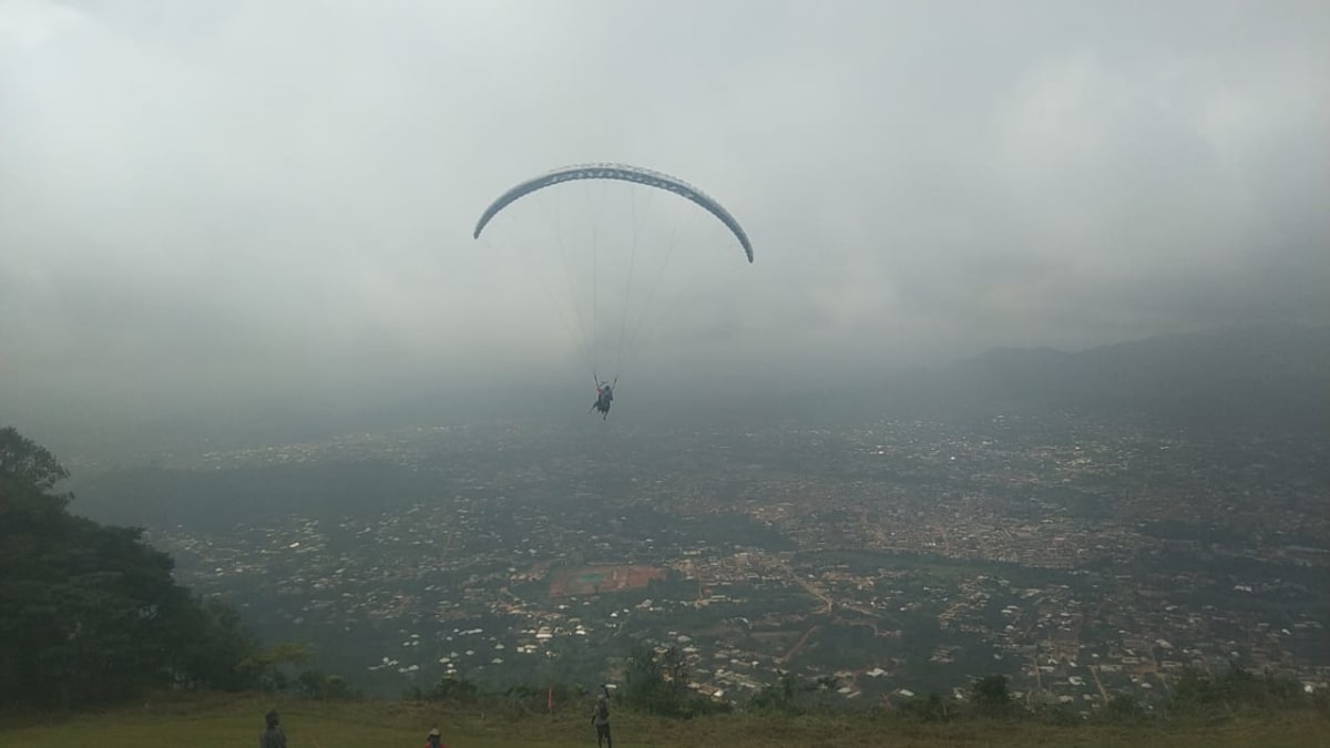Colorful paragliders soaring above green mountains in Kwahu, Ghana during Easter festival