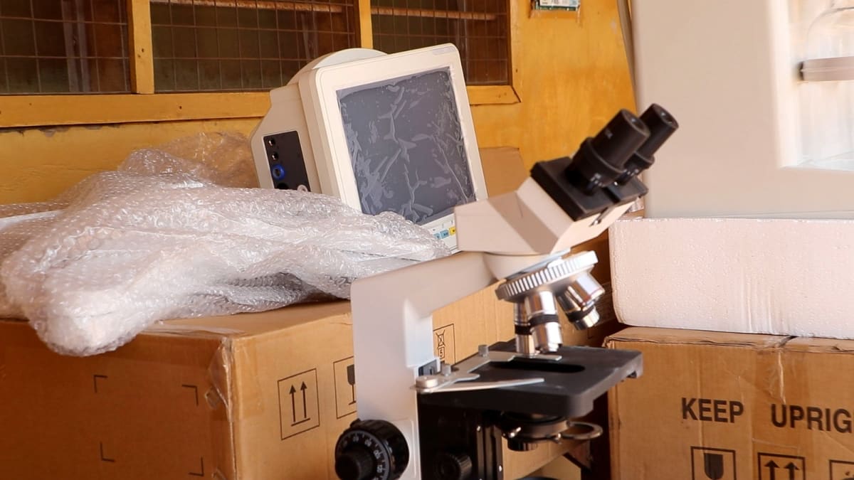 Healthcare workers receiving medical equipment including monitors and oxygen cylinders at rural Ghana clinic