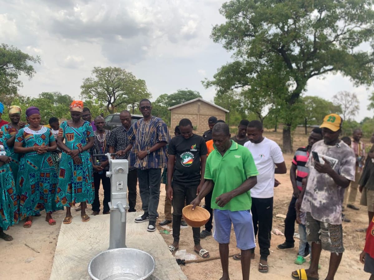 Women celebrating around newly installed water borehole in rural Ghana community
