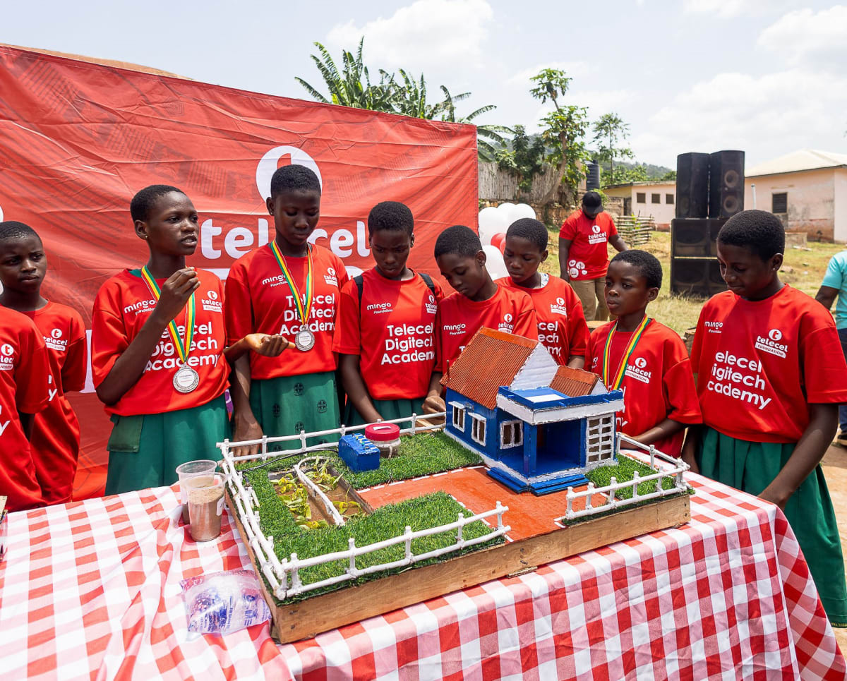 Young Ghanaian students in school uniforms demonstrating robotics projects at graduation ceremony