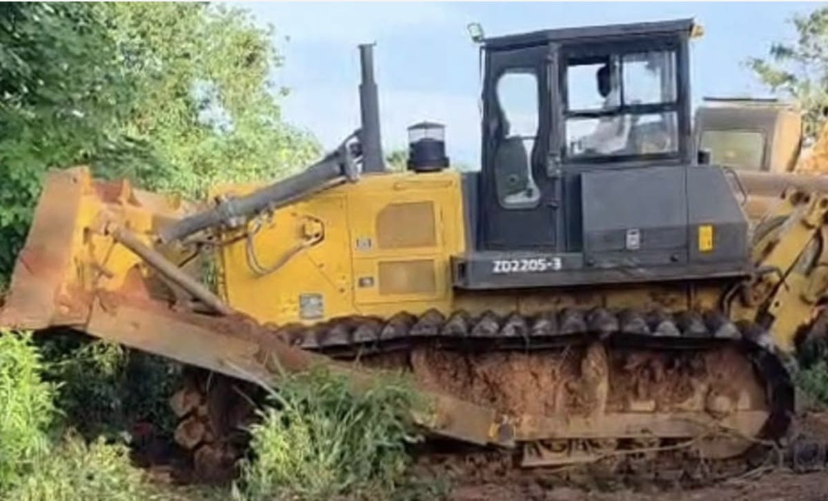 Security officials standing beside seized yellow excavators at dismantled illegal mining site near river