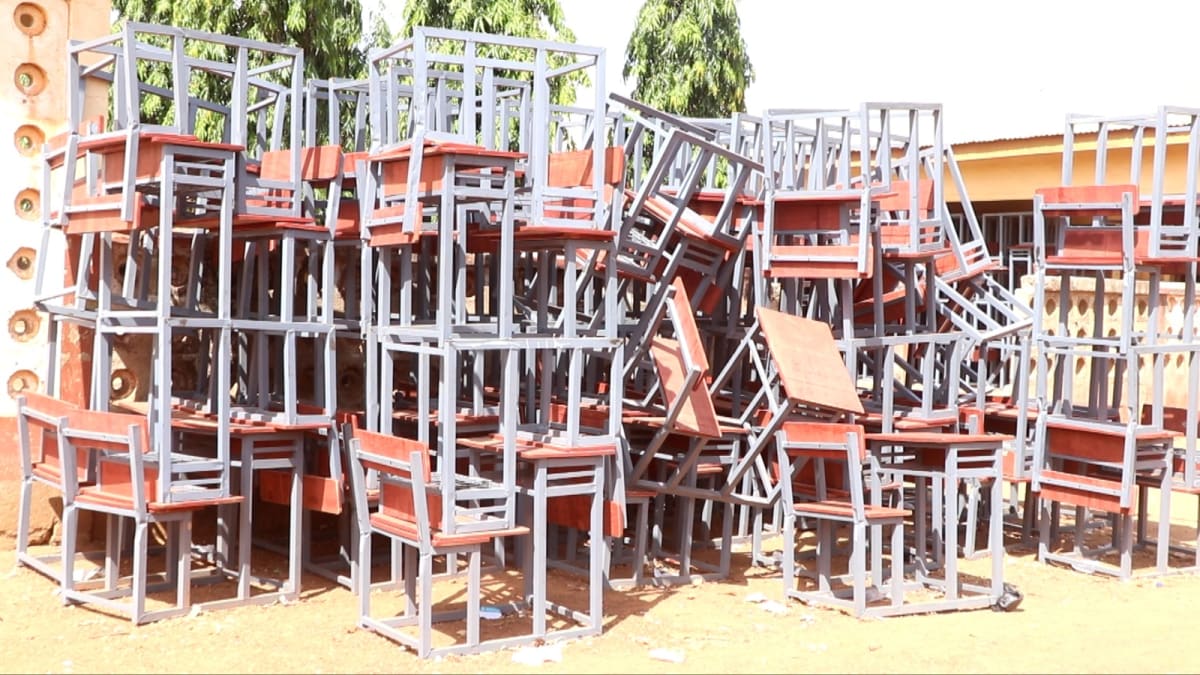 Ghanaian students sitting at new wooden desks in bright classroom after years learning on floors