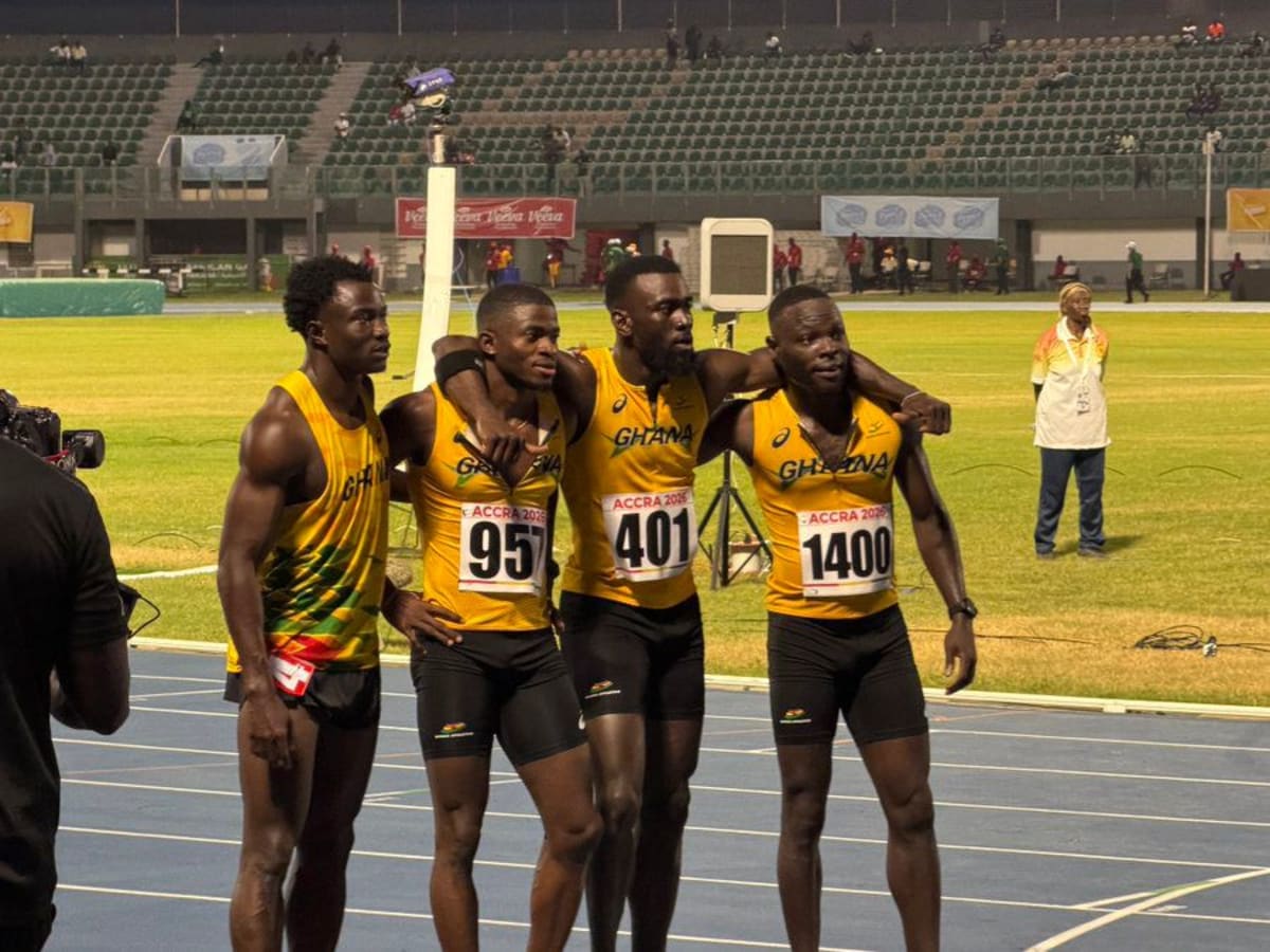 Four Ghanaian relay runners celebrating bronze medal finish at packed University of Ghana Stadium