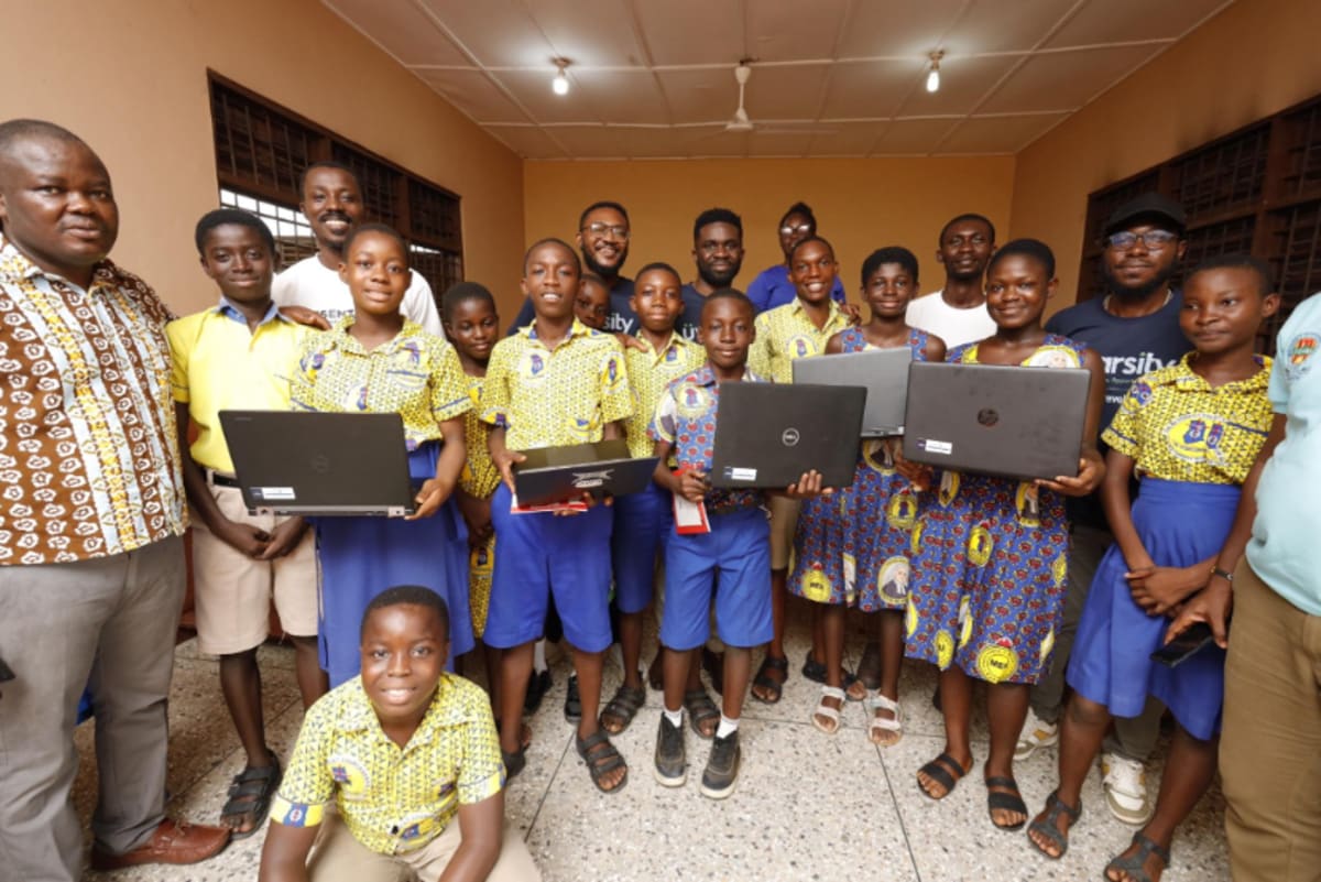 Ghanaian students gather around laptop computers learning AI skills in classroom setting
