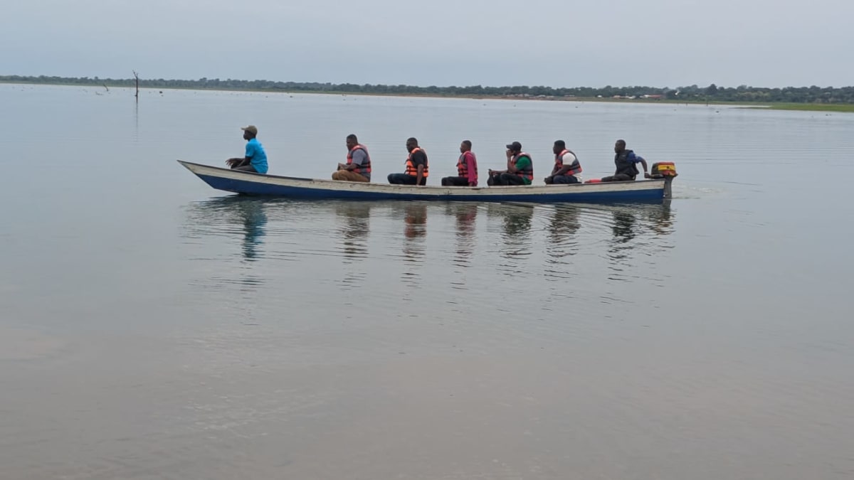 Fishermen with wooden canoes on the Oti River in Ghana listening to weather radio forecast at dawn
