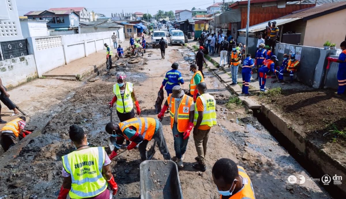 Workers clearing accumulated trash and debris from large drainage channel in Accra Ghana