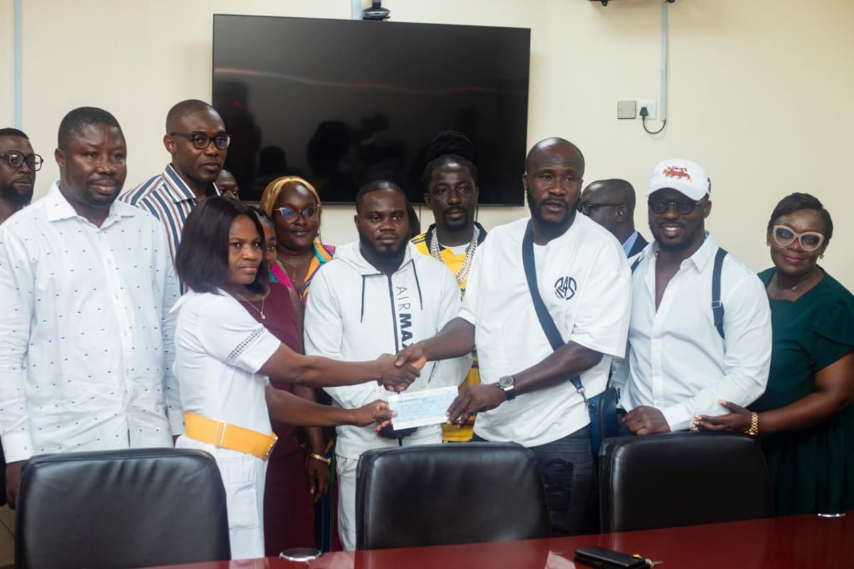 Ghanaian comedian Dr Likee presenting oversized check to hospital staff at Komfo Anokye Teaching Hospital