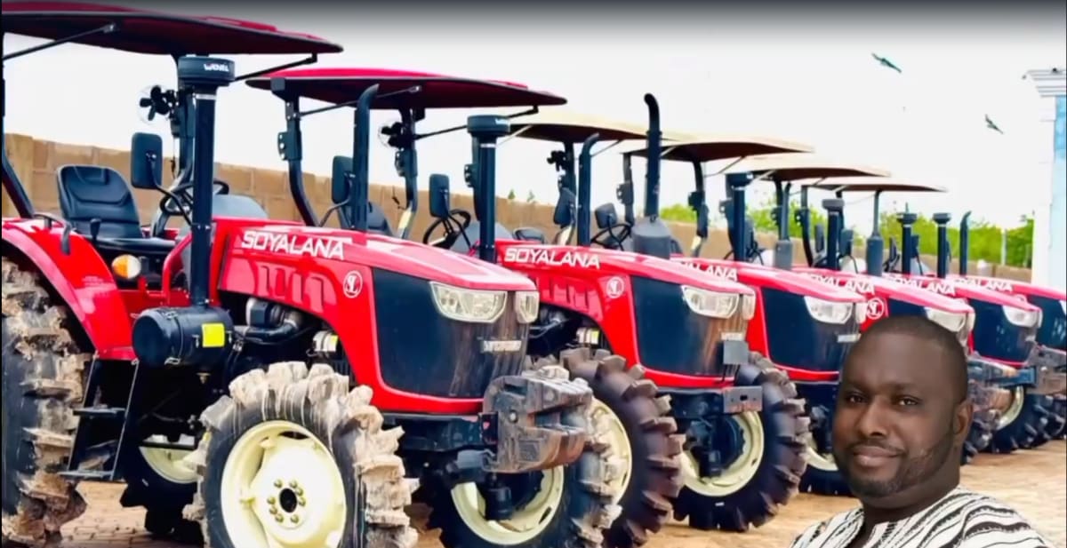 Tractor plowing agricultural field in rural Tolon, Ghana with farmers working nearby