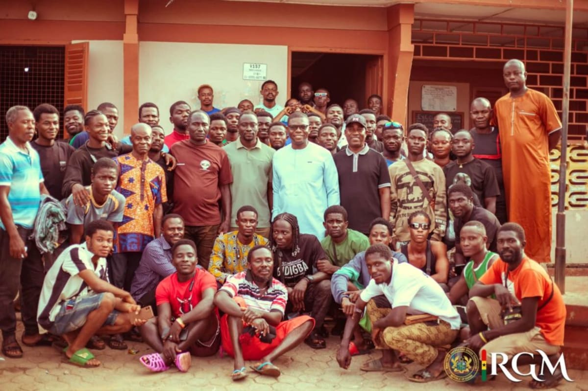 Ghanaian motorcycle taxi riders receiving reflective safety vests from local government official