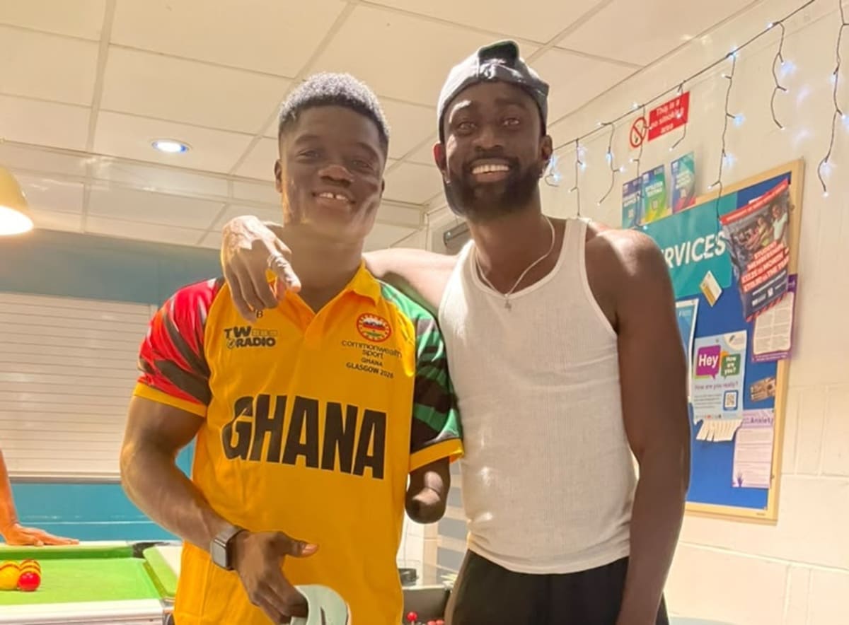 Joseph Paul Amoah presenting racing spikes to teammate Hayford Addae at Commonwealth Games