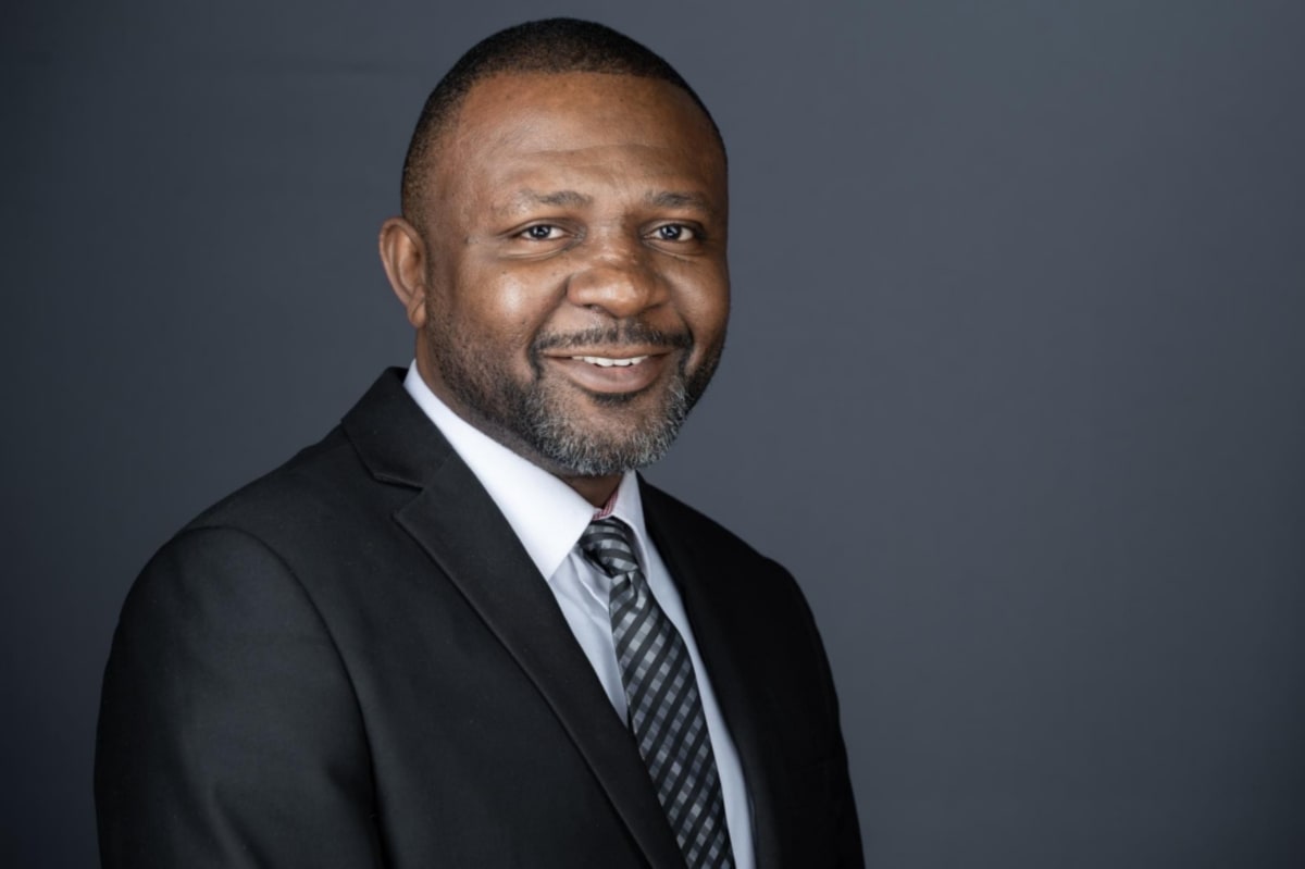 Professor Williams Kwasi Peprah in academic regalia smiling at Andrews University campus