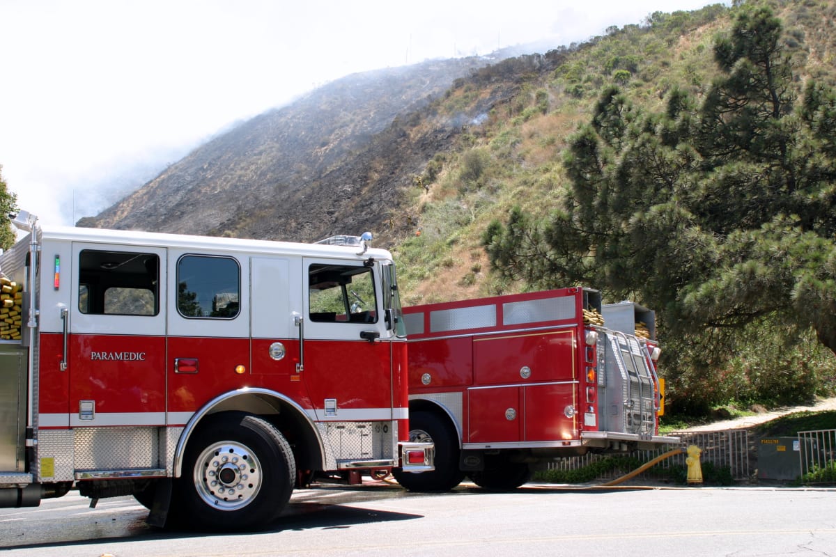 Volunteer firefighter standing in front of rural fire station with housing in background